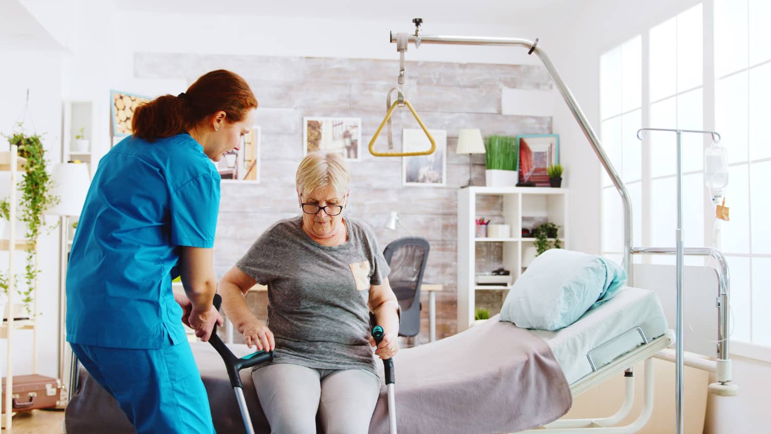 old-disabled-lady-walking-with-help-crutches-nursing-home-while-nurse-is-takinh-care-her